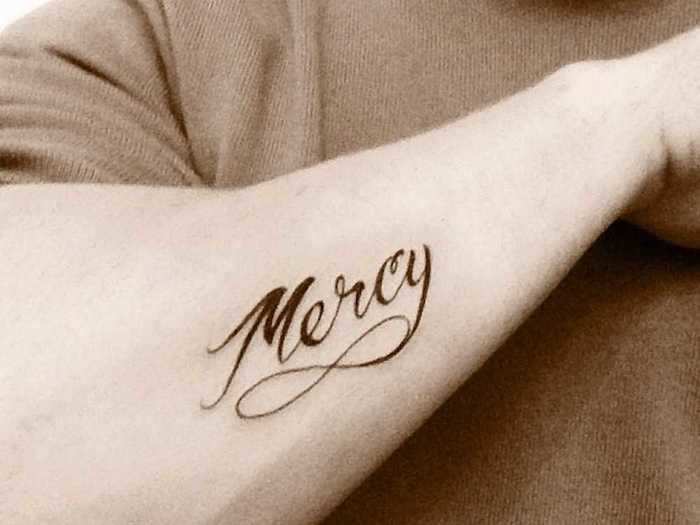 Nick got "mercy" written in cursive across his right arm in October 2012.