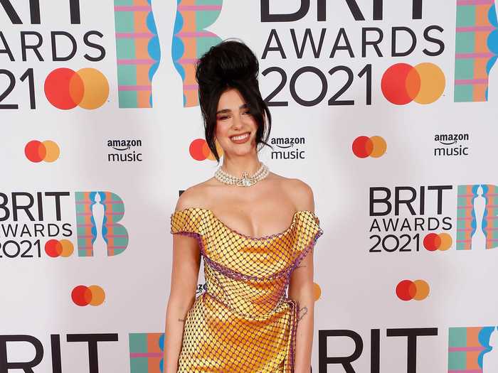 Dua Lipa channeled Amy Winehouse in this golden polka dot gown, thigh-high socks and garters, and beehive hairdo.