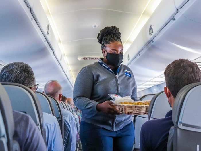 Flight attendants came around with wooden baskets to start the in-flight meal service. On offer were Utz potato chips and Kind bars, as well as small bottles of water.