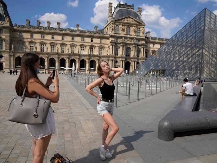 In one photo, a tourist from Germany visiting her French friend is shown posing in front of the famous pyramid at the Louvre.