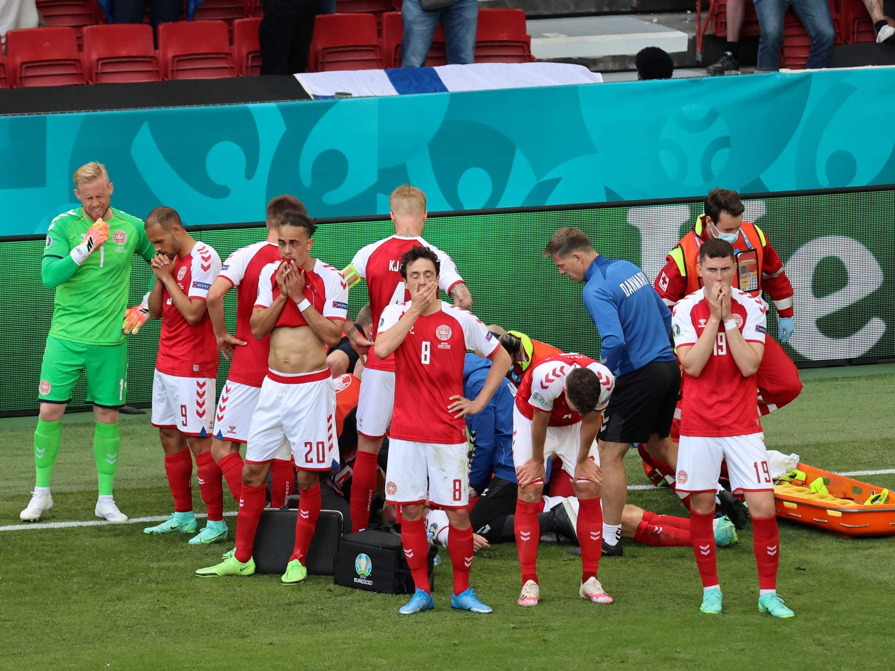 Denmark players surround Christian Eriksen as he receives medical treatment after collapsing on the field.