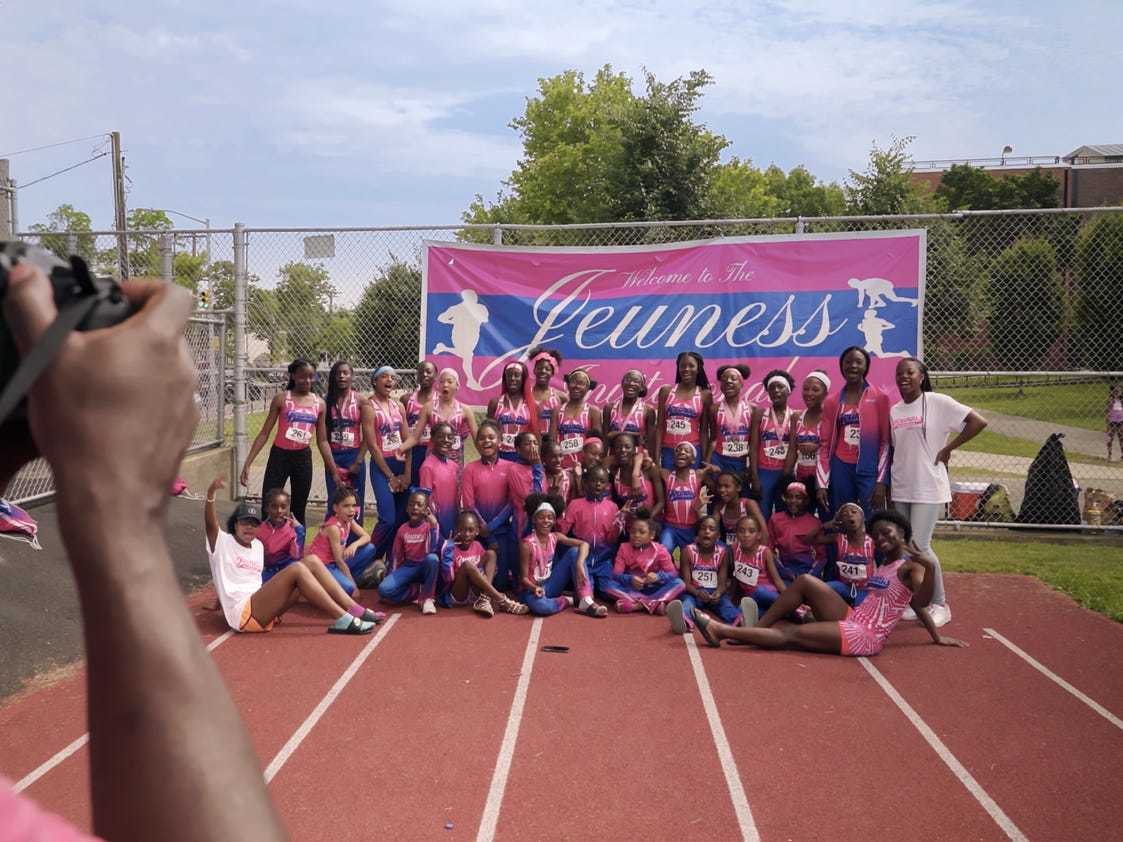 Members of the Jeuness Track Club having their photo taken on a running track.