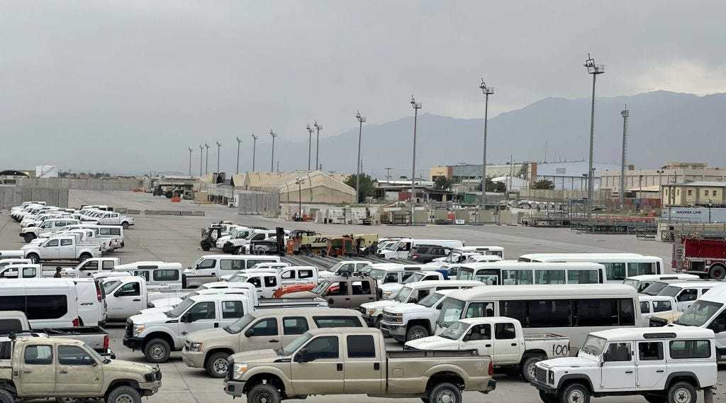 Several white and beige cars and trucks in a parking lot near Bagram Airfield.