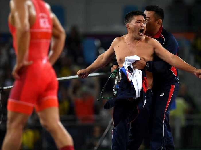 A Mongolian coach stripped off his clothes in protest after his wrestler lost a gold medal for celebrating too early.