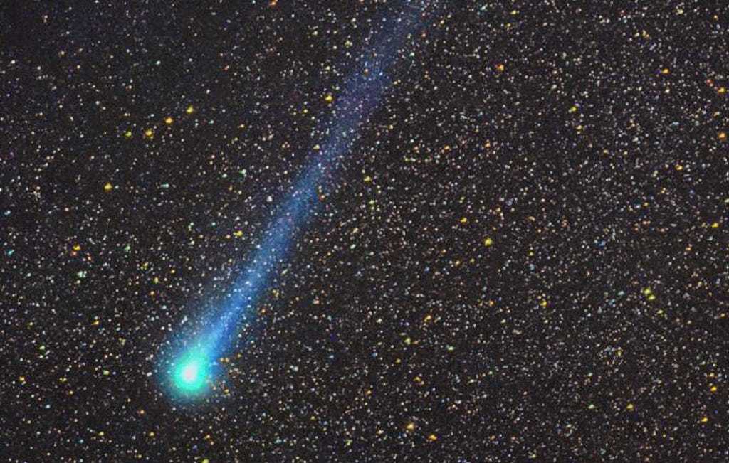 A blue comet against a black night sky with many stars visible.