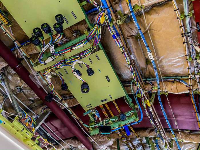 But just above the cabin, the exposed overhead reveals wire harnesses and assemblies, many of which have been removed to be used on other aircraft.