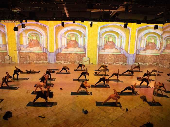 The yoga class took place beneath moving images like the Starry Night and Cafe Terrace at night.