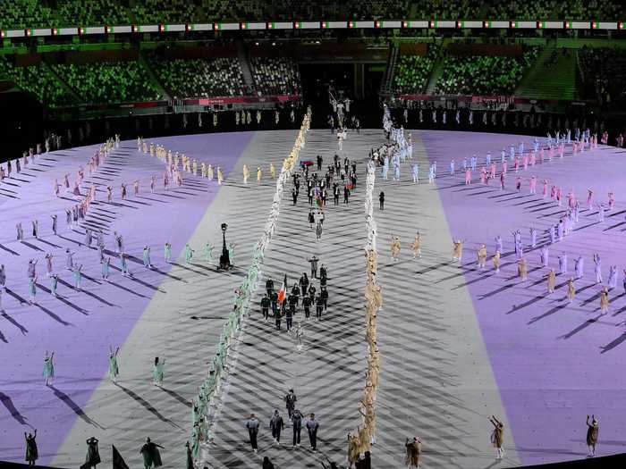 NOW: Tokyo 2020 - A smattering of people maintain their social distance as teams walk in the parade of nations at Tokyo