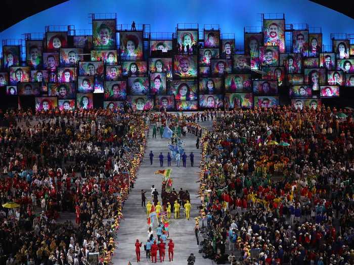 THEN: Rio de Janeiro 2016 - A crowd swells around teams as they process in the parade of nations at the Rio Summer Olympics.