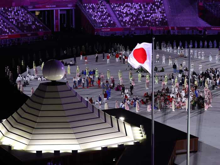 NOW: Tokyo 2020 - The Olympic flag is raised alongside the Japanese flag in front of empty stands at Tokyo