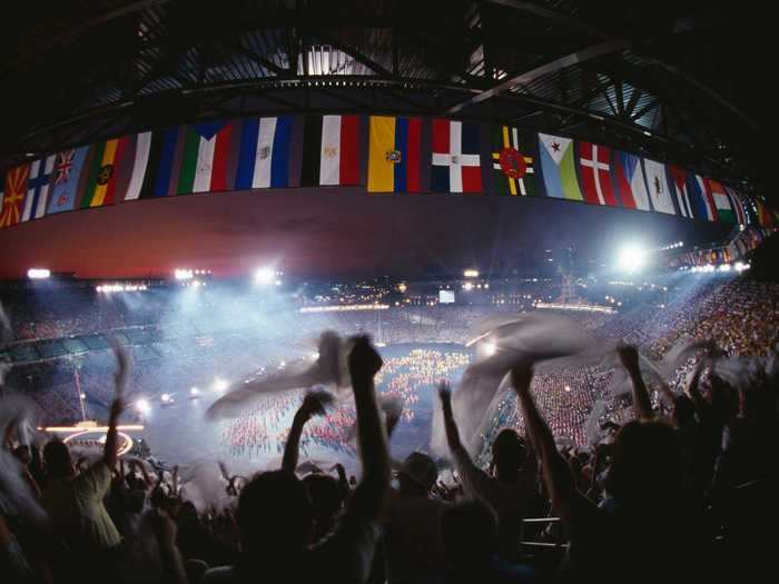 THEN: Atlanta 1996 - Flags from around the world fly as fans cheer at the opening ceremony of the Summer Olympic Games at Atlanta