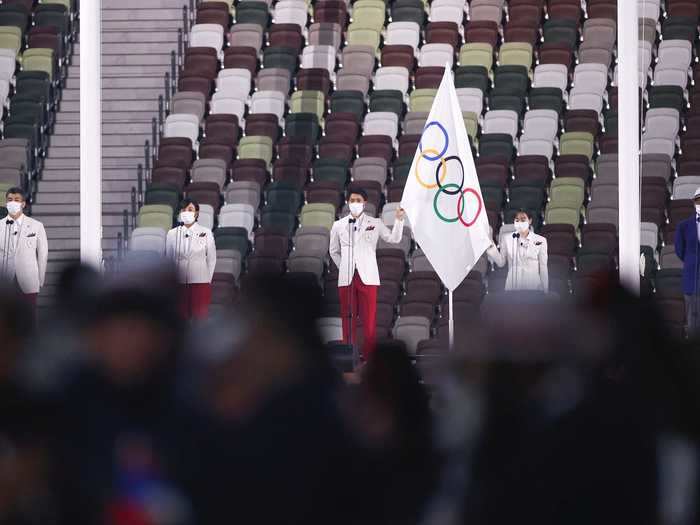 NOW: Tokyo 2020 - The Olympic flag is raised in front of the empty Olympic stadium during the opening ceremony of the Tokyo 2020 Olympic Games.