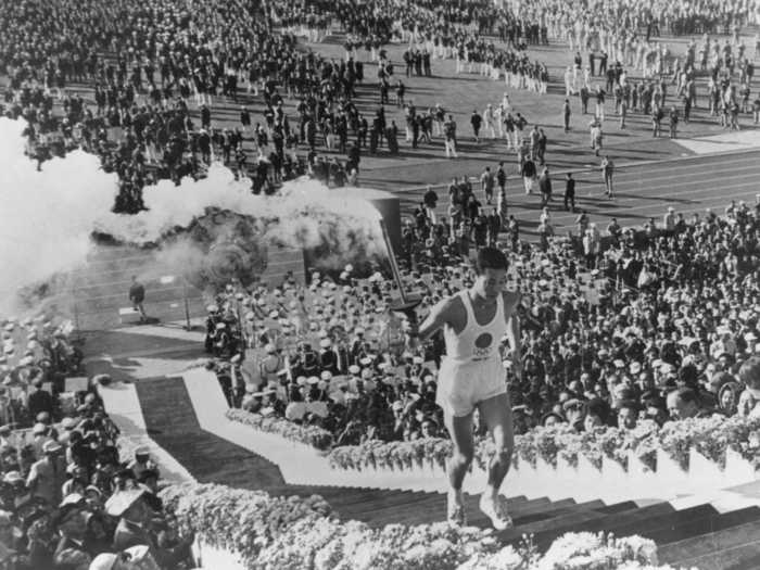 THEN: Tokyo 1964 - Yoshinori Sakai, a student born in Hiroshima on the day the first atomic bomb devastated the city, carries the torch to light the cauldron during the opening ceremony for the 1964 Tokyo Summer Olympics.