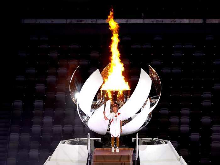 NOW: Tokyo 2020 - Naomi Osaka of Team Japan lights the Olympic cauldron with the Olympic torch during the opening ceremony at the empty Olympic Stadium in Tokyo.