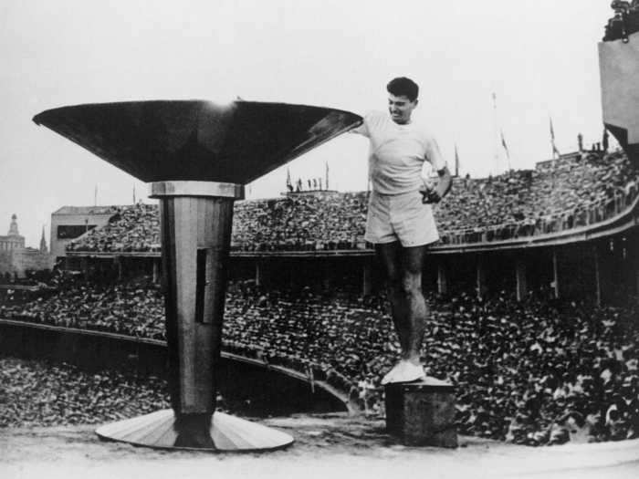 THEN: Melbourne 1956 - Ron Clarke of Australia lights the Olympic Torch at a packed opening ceremony for the 17th Olympic Games.