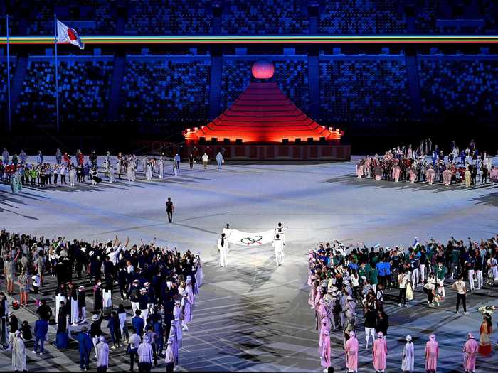 NOW: Tokyo 2020 - A flag donning the Olympic rings is carried towards the Olympic cauldron during the opening ceremony in Tokyo.