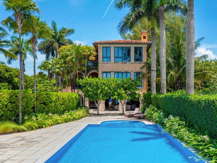 Outside, an infinity pool is shaded by palm trees and kept private by a thick hedge.