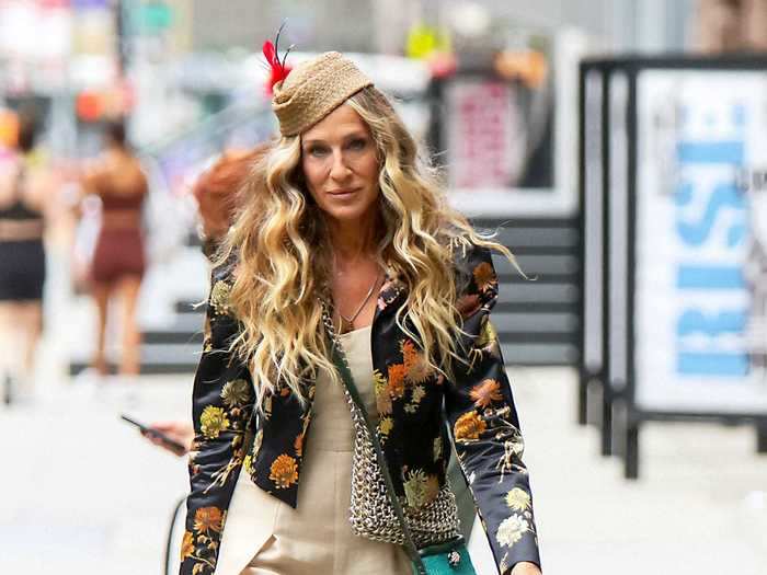 In another notable and extremely Carrie Bradshaw look, Parker wore a cream linen Claude Montana jumpsuit, Dries Van Noten blazer, and feather hat.