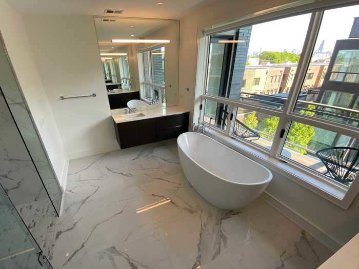 The bathroom has marble floors, a shower, and a bathtub.