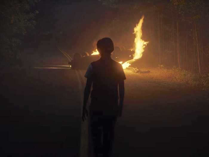 An unknown person watches a burning car in this ominous shot. Could this be Mike or Will?