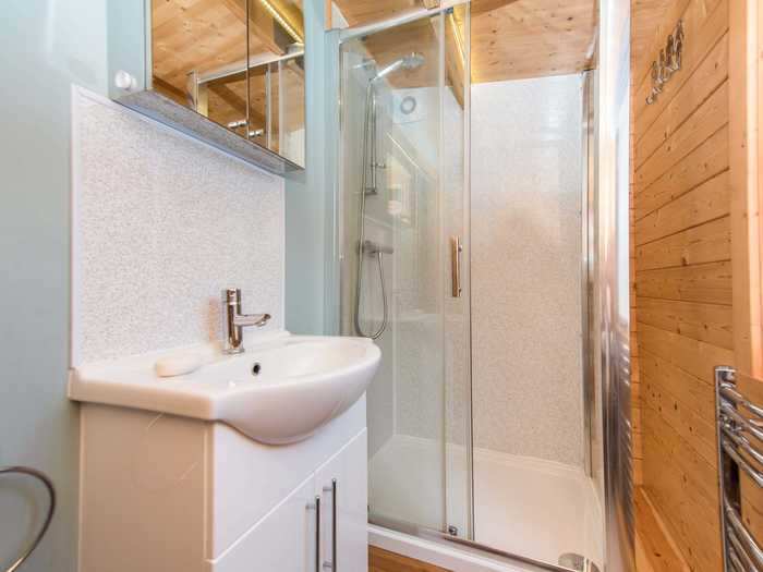 The second bathroom has a glass shower and storage cabinets.