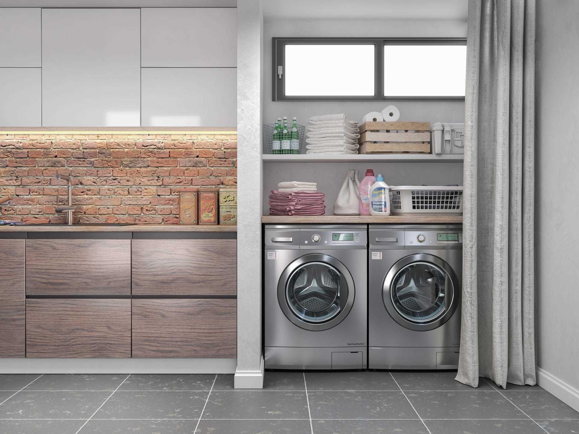Laundry room with wood flooring and grey appliances.
