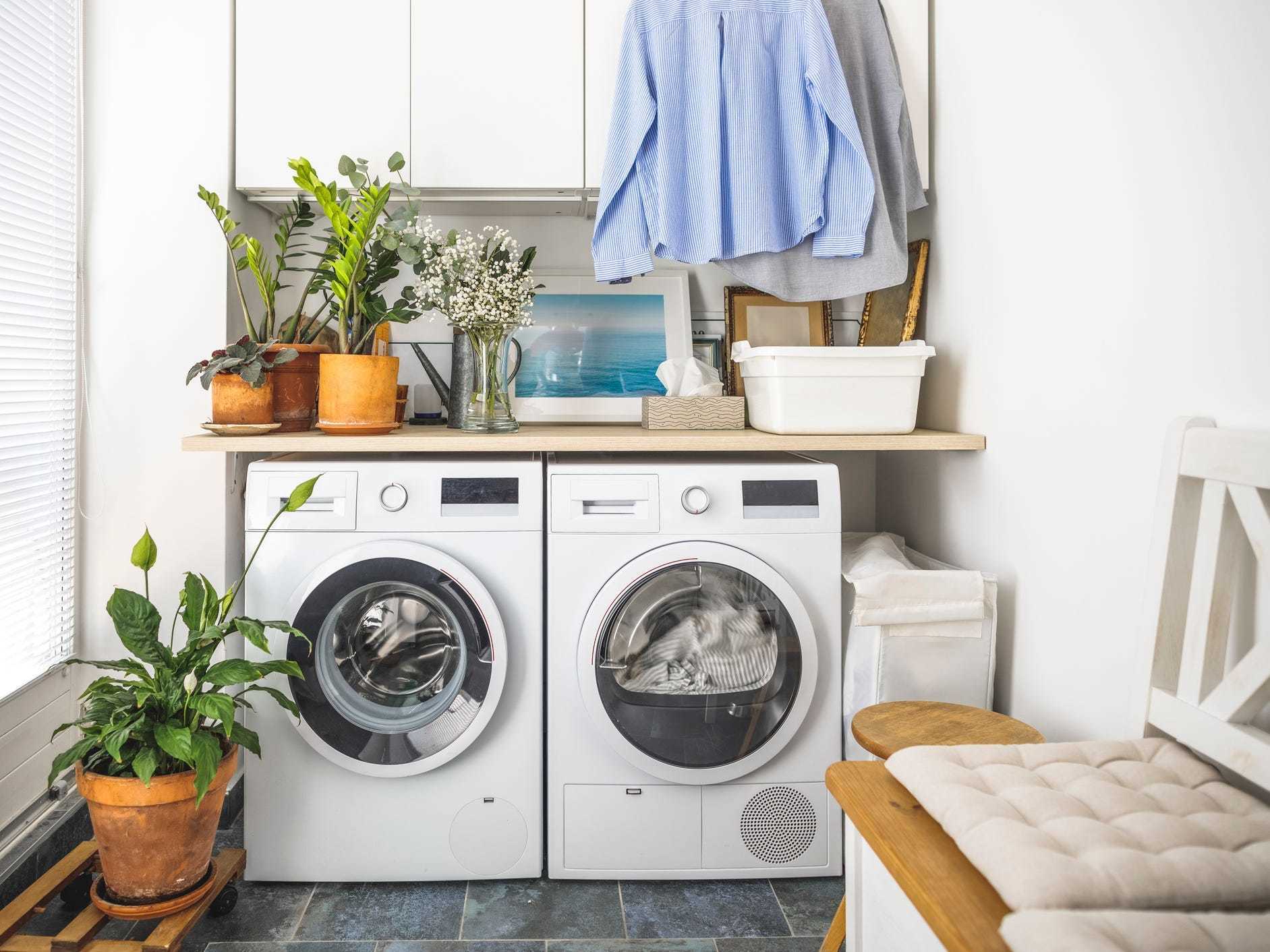 A bright laundry room with plants and chairs.
