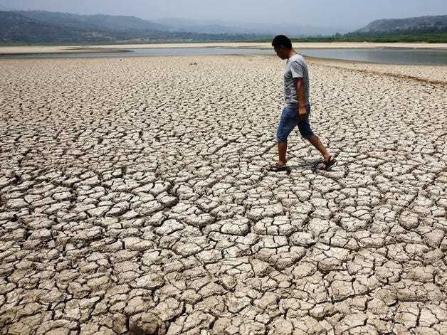 A man walks through the dried-up bed of a reservoir in Sanyuan county, Shaanxi province July 30, 2014. REUTERS/Stringer 