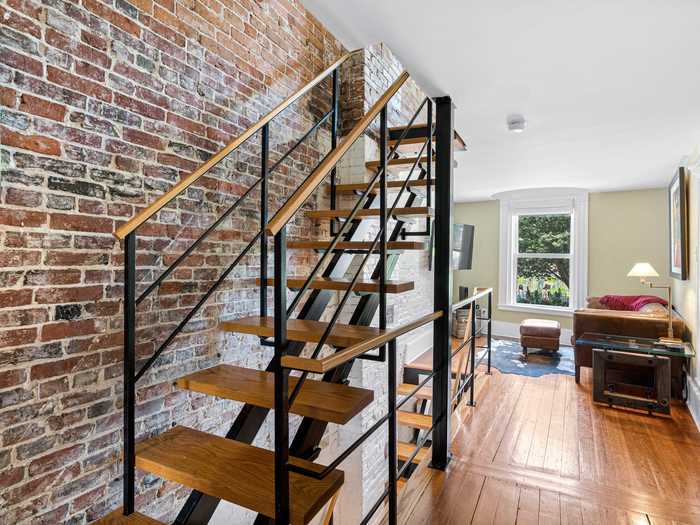 Past the living space, a narrow hallway leads to a staircase.