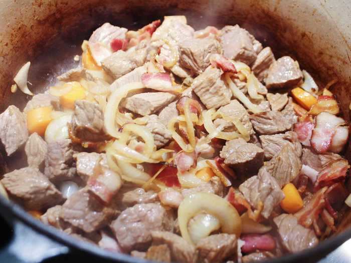 I added the bacon and beef back into the pot with the vegetables, seasoned it, and sprinkled flour over the top.