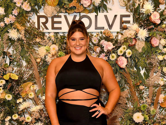 Remi Bader arrived at the Revolve gallery presentation in a black dress with a thigh-high slit and crisscross straps across her torso.