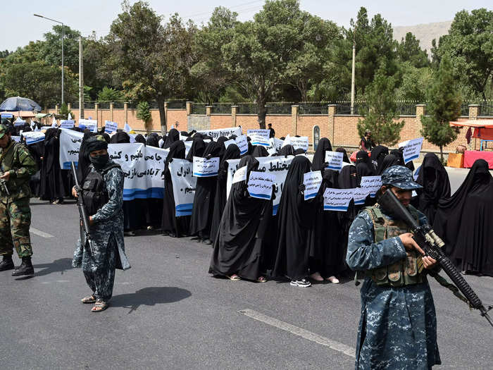 Veiled women attended a pro-Taliban rally while flanked by armed Taliban fighters.