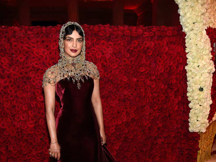 Priyanka Chopra looked chic in a burgundy velvet Ralph Lauren gown topped off with a gold beaded hood that took over 250 hours to make.