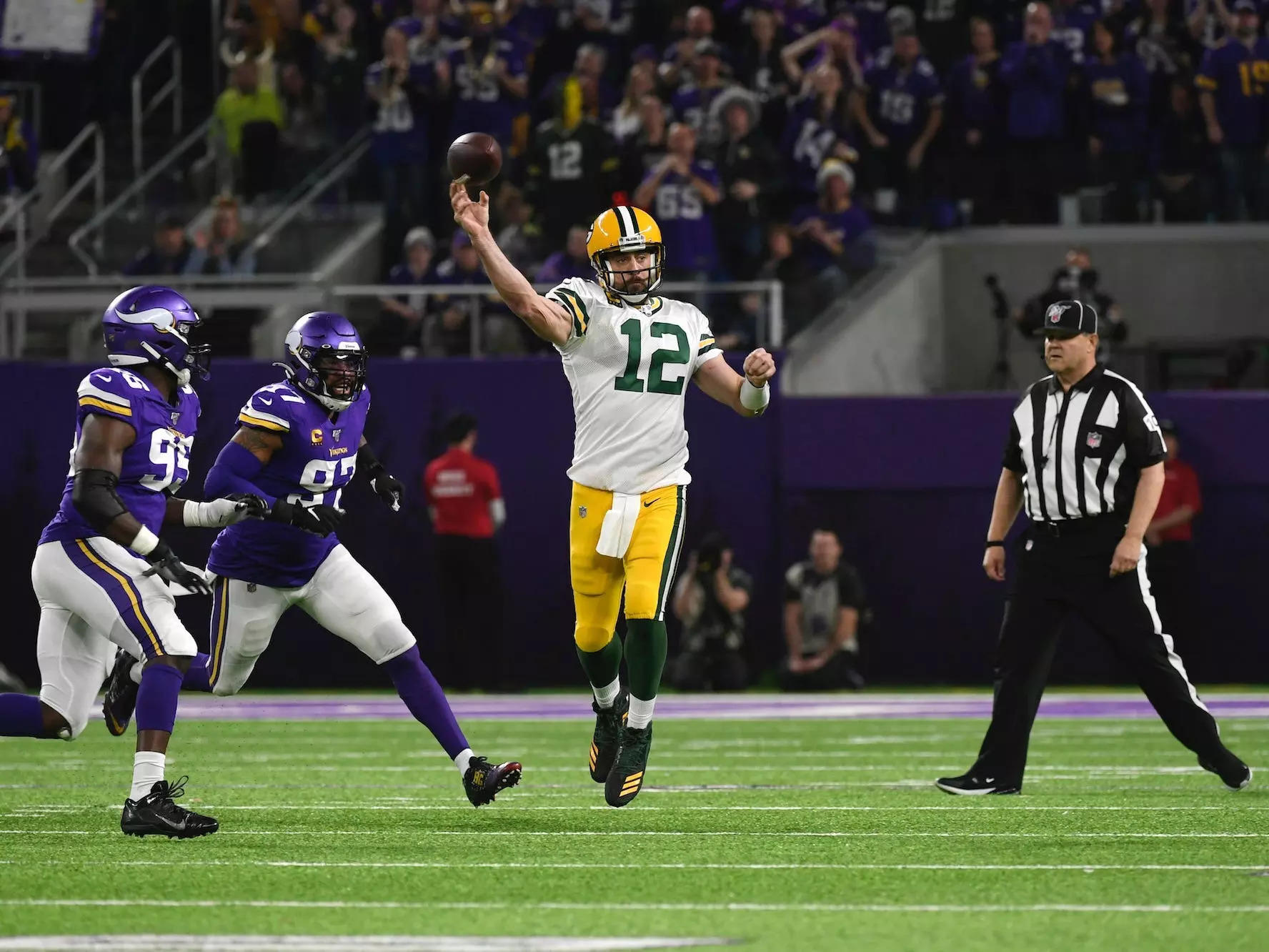Aaron Rodgers makes a throw across his body while being chased by Vikings defenders.