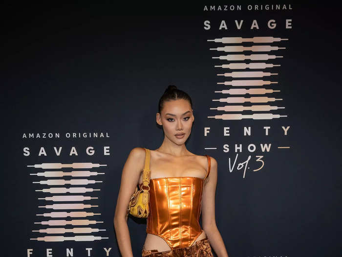 Jessie Li made a statement in a copper-colored bustier top with brown pants and a mustard bag.