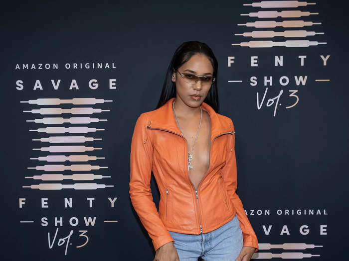 Model Aleali May paired an unzipped orange jacket with jean shorts and knee-high orange boots. Sunglasses completed her casual look.