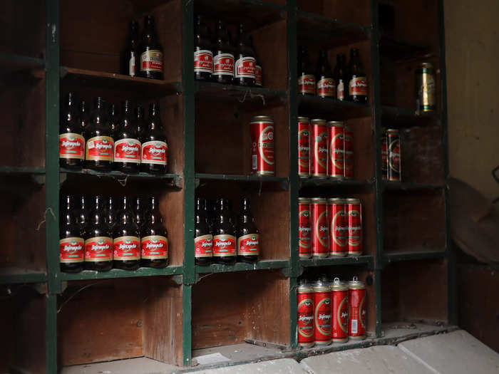 Empty beer cans and bottles sit on shelves inside an abandoned shop in the village of Papratna, Serbia.