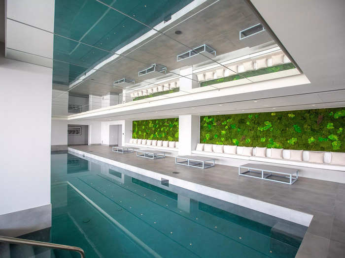 Multiple swimming pools dot the property, like this one indoors, in a room with a living wall and a mirror on the ceiling...