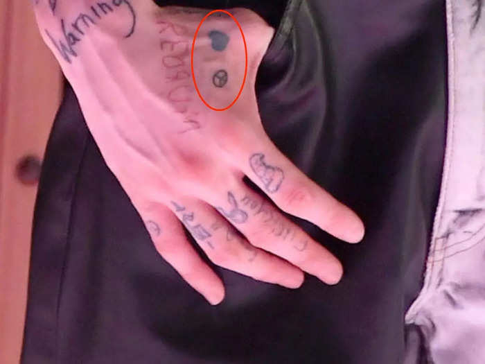 There are two micro-tattoos on his right hand.