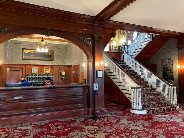 Stepping inside the hotel felt like traveling back in time. Patterned carpet fills the reception area, dark oak paneling covers the walls, and a grand staircase leads guests upstairs.