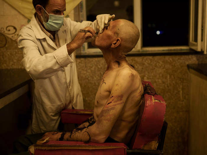 A drug user detained during a Taliban raid has his face shaved.