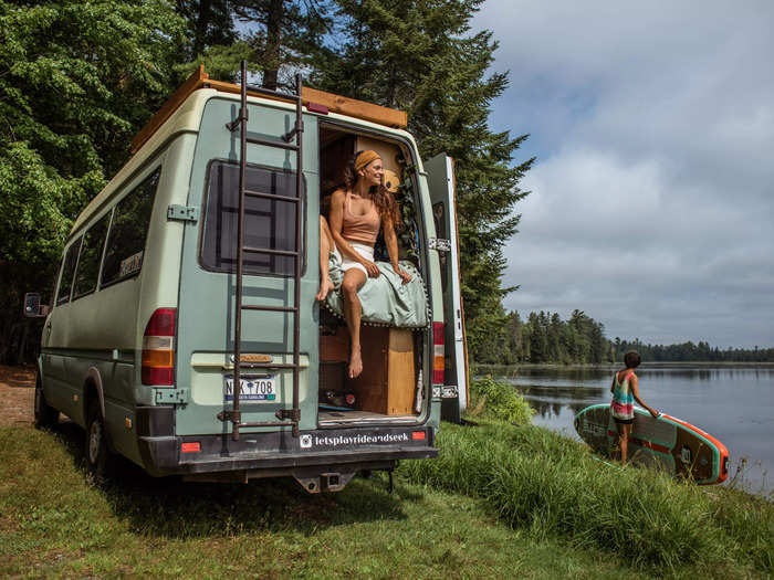 A ladder leads up to the deck behind the van.