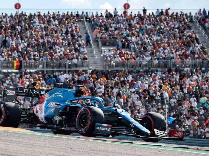 Alpine driver Fernando Alonso speeds around Turn 1 in front of the fans.