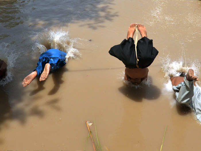 Children swim in dirty puddles to escape the heat.