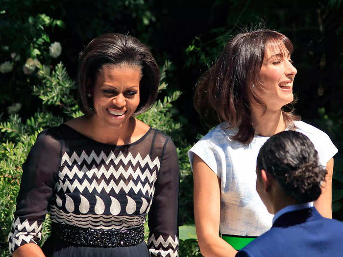 In May 2011, Obama served food to military families in a black and white printed dress with sheer sleeves and a beaded belt.