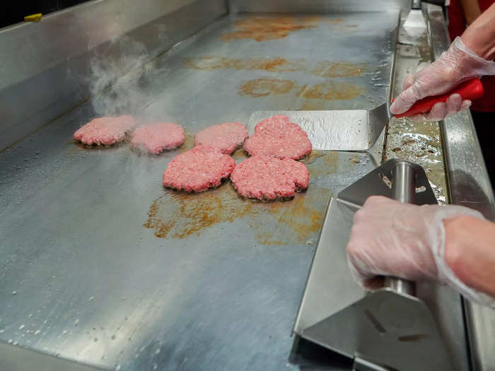 Once the patty number is called out, they get slapped down onto the metal surface in stage one of the three-stage grill.