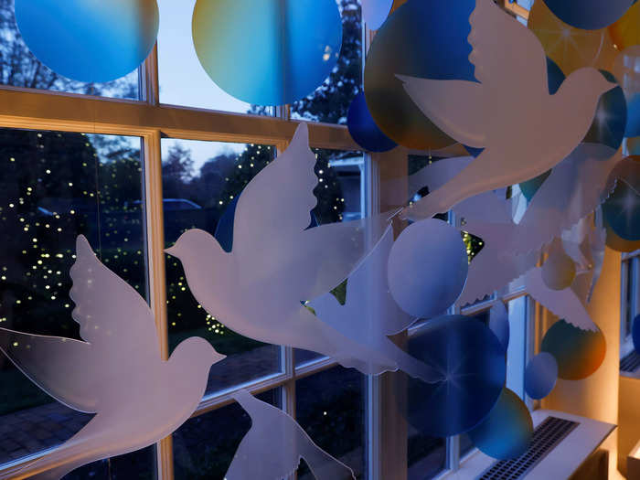 Cutouts of doves hang amid the window decorations.