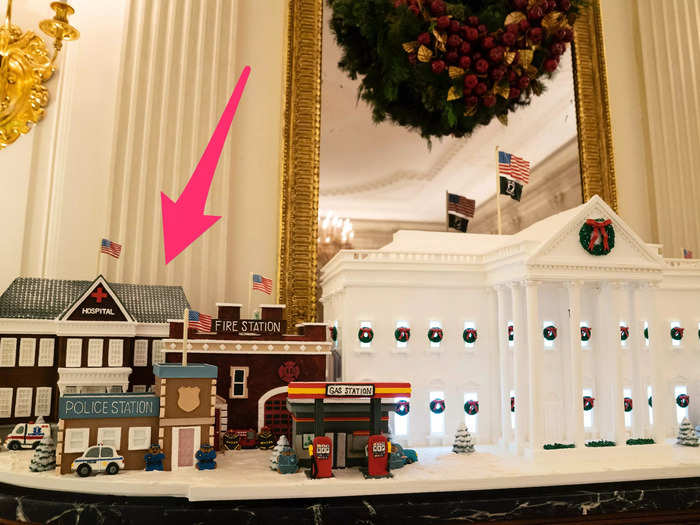 The gingerbread buildings on either side of the official 2021 Gingerbread White House honor frontline and essential workers.