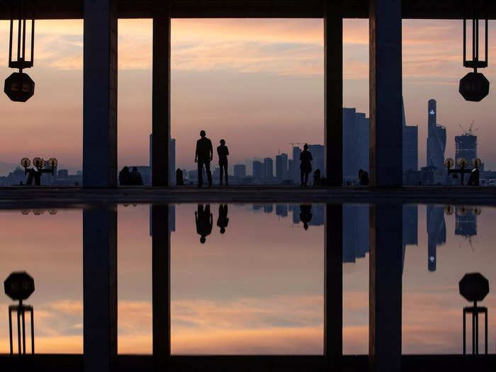 This photo looks like a surreal, multidimensional setting, but the people in it are simply reflected in a puddle during a sunset in Moscow, Russia.