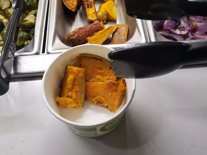 Squeeze 3 pieces of sweet potato from the salad bar onto the side of the cup.